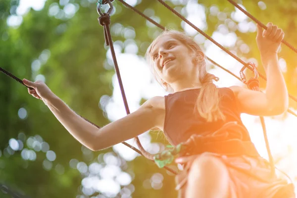 Mädchen wandert in Sicherheitsausrüstung im Seilpark — Stockfoto