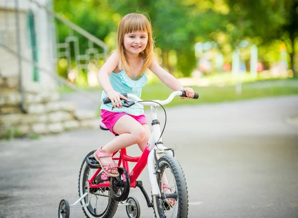 Красивая улыбающаяся маленькая девочка на велосипеде — стоковое фото