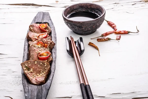 Carne picante oriental sobre plato de madera sobre fondo blanco . — Foto de Stock