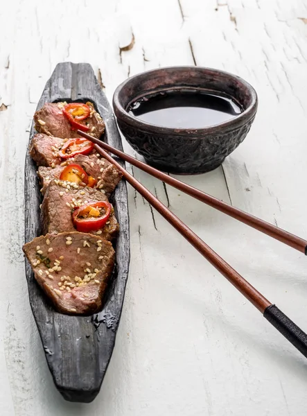 Carne picante oriental sobre plato de madera sobre fondo blanco — Foto de Stock