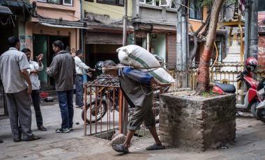 İnsan Katmandu sokaklarda sırtında bir çuval taşımak