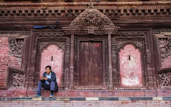 伝統的なネパールの寺院の壁のそばに座って男 — ストック写真