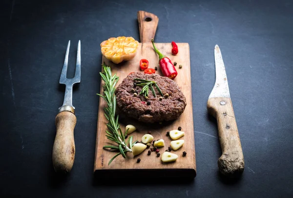 Свежая котлета из говяжьего бургера на кухонной доске — стоковое фото