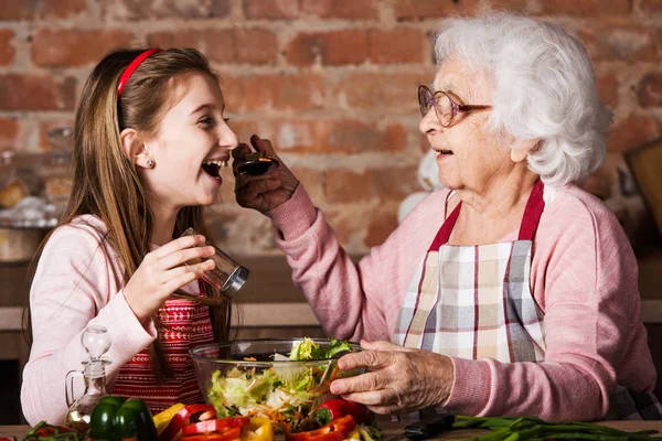 Granny ger för att prova en sallad till barnbarnet — Stockfoto