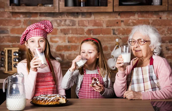 Systrar med mormor sitter vid bord — Stockfoto