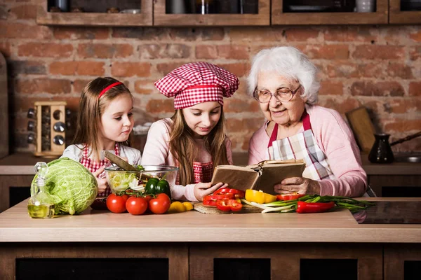 Farmor med två barnbarn läser recept — Stockfoto