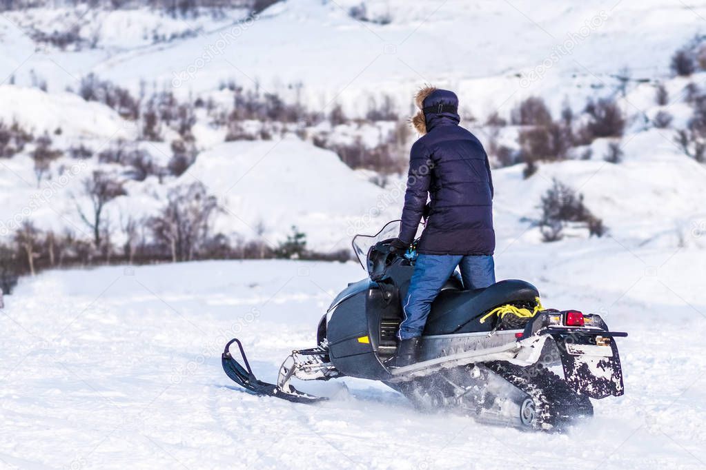 Man rides on snowmobile through snowy fields
