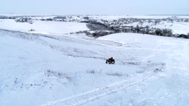 Colpo aereo di uomo alla guida di ATV al campo invernale — Video Stock