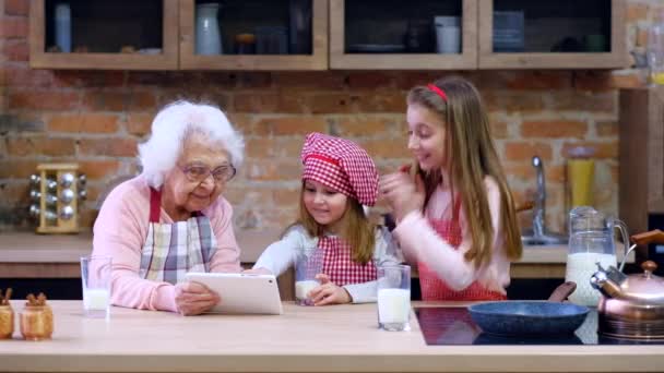 孫娘とキッチンでタブレットと祖母 — ストック動画