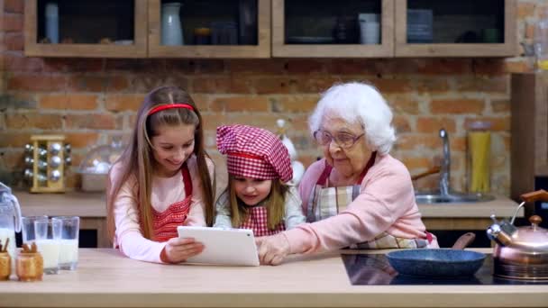 Enkelin und Großmutter mit Tablet in der Küche — Stockvideo