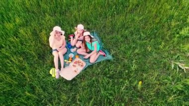 Piknik örtüsünde oturan kızlar