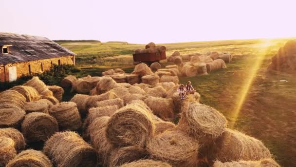 Две девочки на стоге сена в летнем поле — стоковое видео