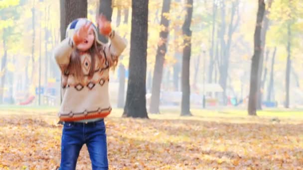 Kleines Mädchen springt auf Herbstblättern — Stockvideo