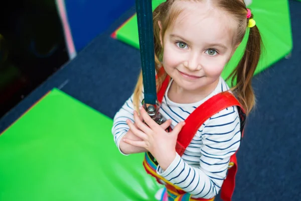 Active little girl in safety harness on climbing wall — Stock Photo, Image