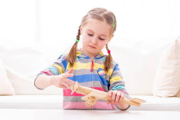 Девочка Смили играет с деревянным игрушечным самолетом — стоковое фото