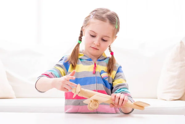 Menina sorridente brincando com avião de brinquedo de madeira — Fotografia de Stock