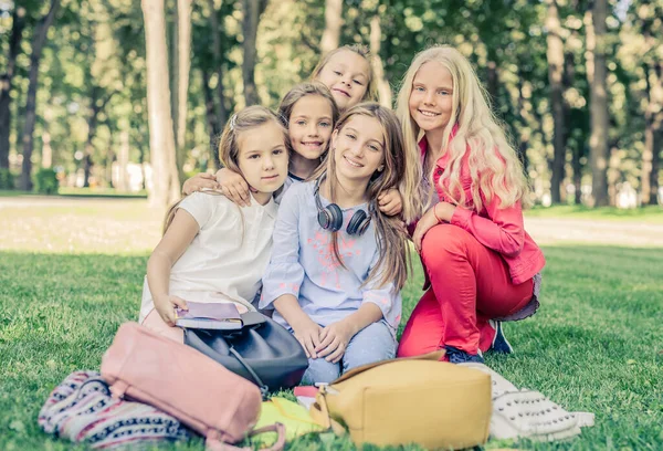 Hübsche lächelnde kleine Mädchen sitzen zusammen im Park — Stockfoto