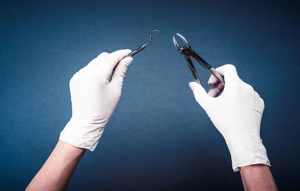 Manos en guantes que sostienen herramientas dentales de cirugía — Foto de Stock