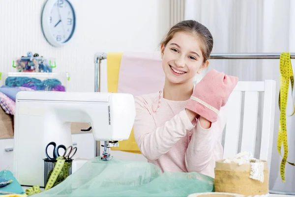 Leende liten flicka som arbetar på symaskinen — Stockfoto