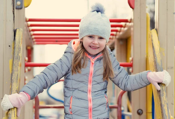 Kind van achter de ladder op de speelplaats — Stockfoto