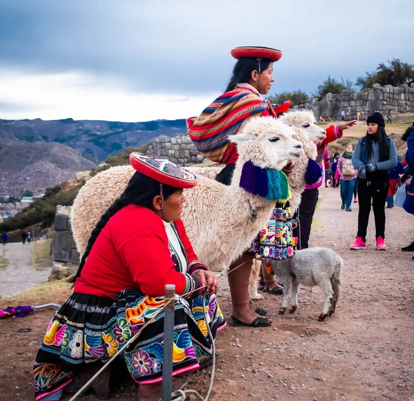 Vista de las mujeres en ropa nacional con lamas en el fondo del paisaje Sacsayhuaman con los turistas — Foto de Stock