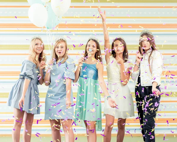Bastante niñas adolescentes sonrientes en vestidos alegremente levantaron las manos juntos y ejecutar slappers con destellos en la fiesta de cumpleaños — Foto de Stock
