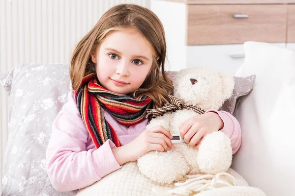 Kleines krankes Mädchen misst Temperatur von Teddybären — Stockfoto