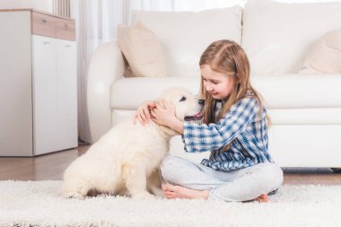 Kız evde retriever köpek yavrusu ile oturan