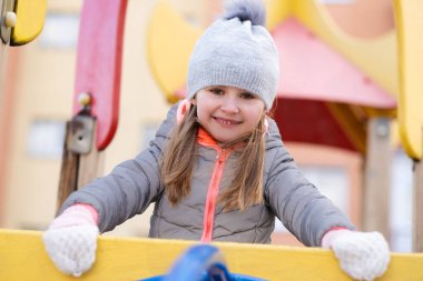 Oyun parkındaki merdivenin arkasındaki çocuk.