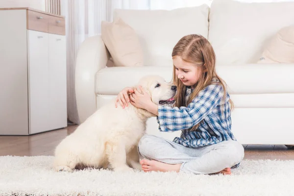 Kız evde retriever köpek yavrusu ile oturan — Stok fotoğraf