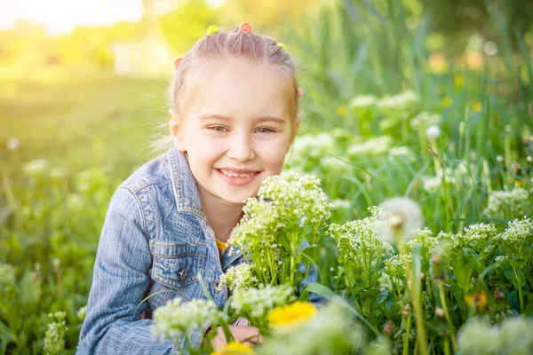 Menina sorridente sentada no campo de grama — Fotografia de Stock