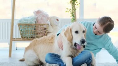 Gülümseyen küçük kız sevimli köpeğe sarılıyor.
