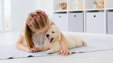 Küçük kız esneyen köpek patisini tutuyor.