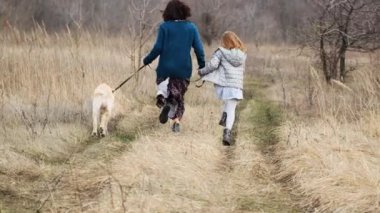 Kadın ve kız köpekle koşuyor.