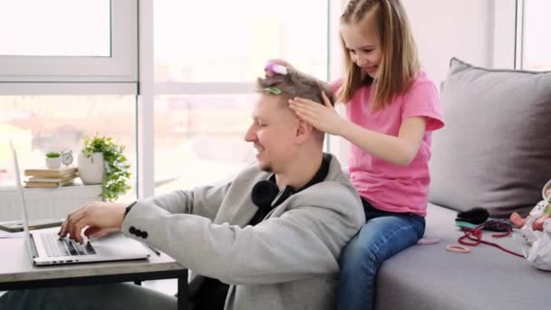 Girl making hairstyle to working father — Stock Video