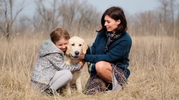 Madre e hija acariciando perro — Vídeo de stock