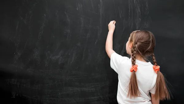 Little girl against blackboard — Stock Photo, Image