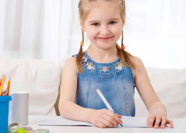 Mała dziewczynka odrabia lekcje za biurkiem. — Zdjęcie stockowe