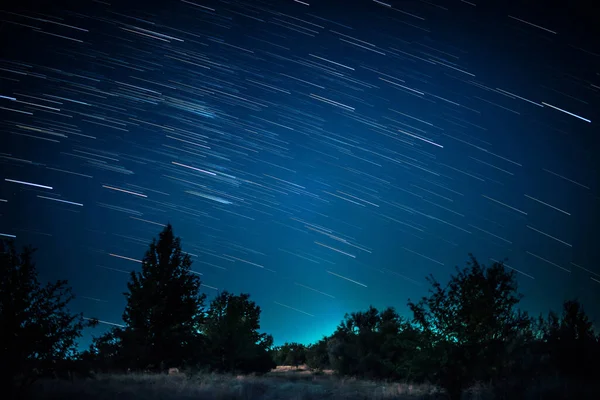Trilhas estelares acima da floresta escura — Fotografia de Stock