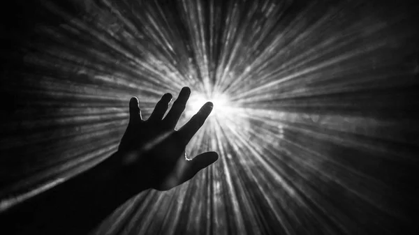 Hand reaches out to touch the light — Stock Photo, Image