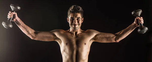 Un uomo che allunga le braccia verso l'esterno facendo una standing Dumbbell Chest Fly Studio composito su nero . — Foto Stock