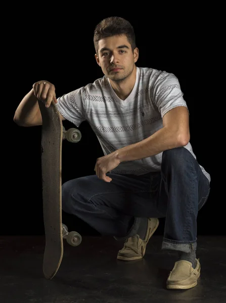 Retrato de um patinador masculino segurando um skate e olhando para a câmera — Fotografia de Stock