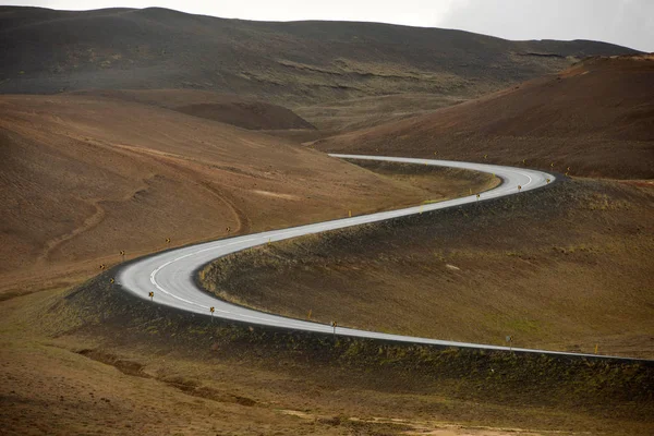 Camino curvo que conduce a través de una colina en Islandia — Foto de Stock