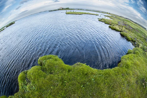 Corpo de água do lago ao lado de um corpo de terra de grama — Fotografia de Stock