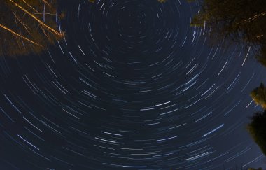 Koyu mavi gökyüzünde dönen yıldız izi deseni, uzun pozlama