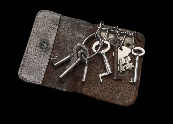 Stare klucze w kluczu w kluczowych portfel ze skóry na czarnym tle — Zdjęcie stockowe