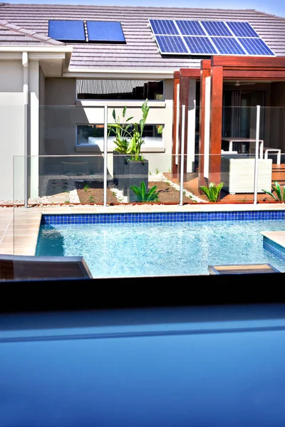 En vy av en modern pool och ett hus med solpaneler o — Stockfoto