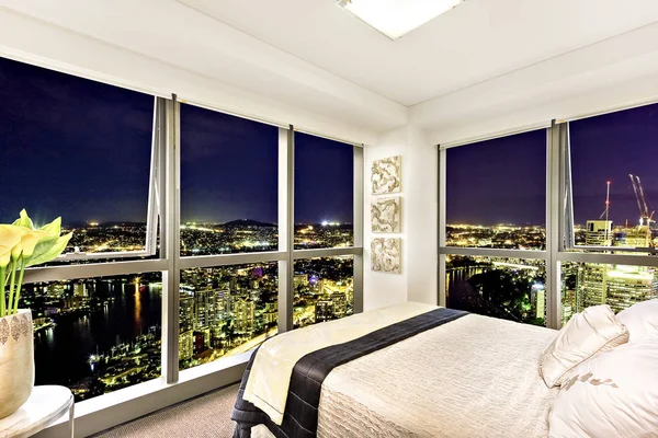 Comfortable bed near city view at night.