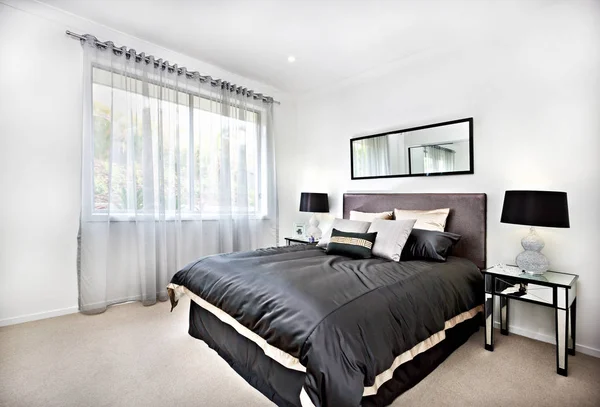 Modern bedroom with black decoration and mirror beside lamps — Stock Photo, Image