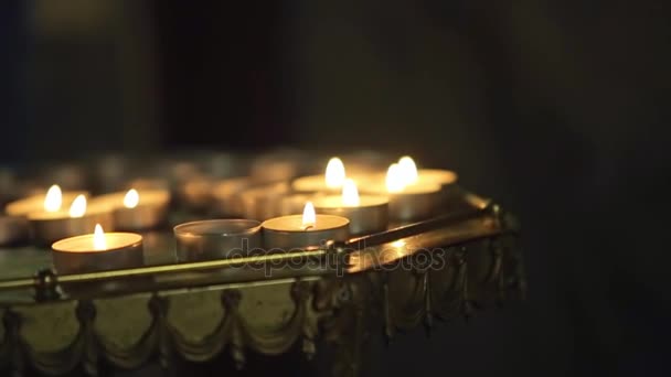 Многие свечи пламени светятся в темной церкви — стоковое видео